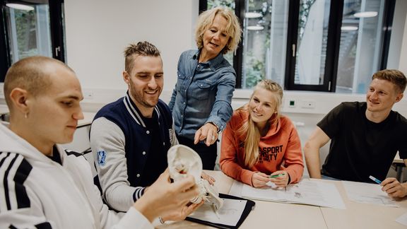 Studierende betrachtet Modell einer Wirbelsäule in Gruppenarbeit
