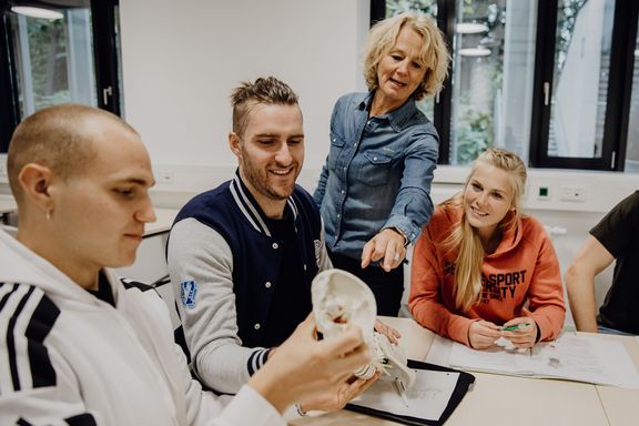Studierende betrachtet Modell einer Wirbelsäule in Gruppenarbeit
