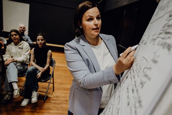 Dozentin beschriftet Whiteboard vor Studierenden
