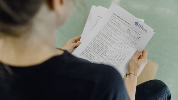 Studierende betrachtet Fragebogen der Deutschen Sporthochschule
