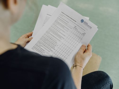 Studierende betrachtet Fragebogen der Deutschen Sporthochschule
