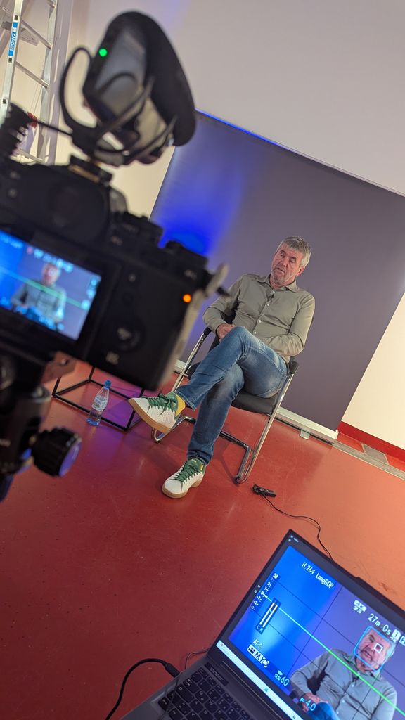 Interviewte Person vor Leinwand und Kamera
