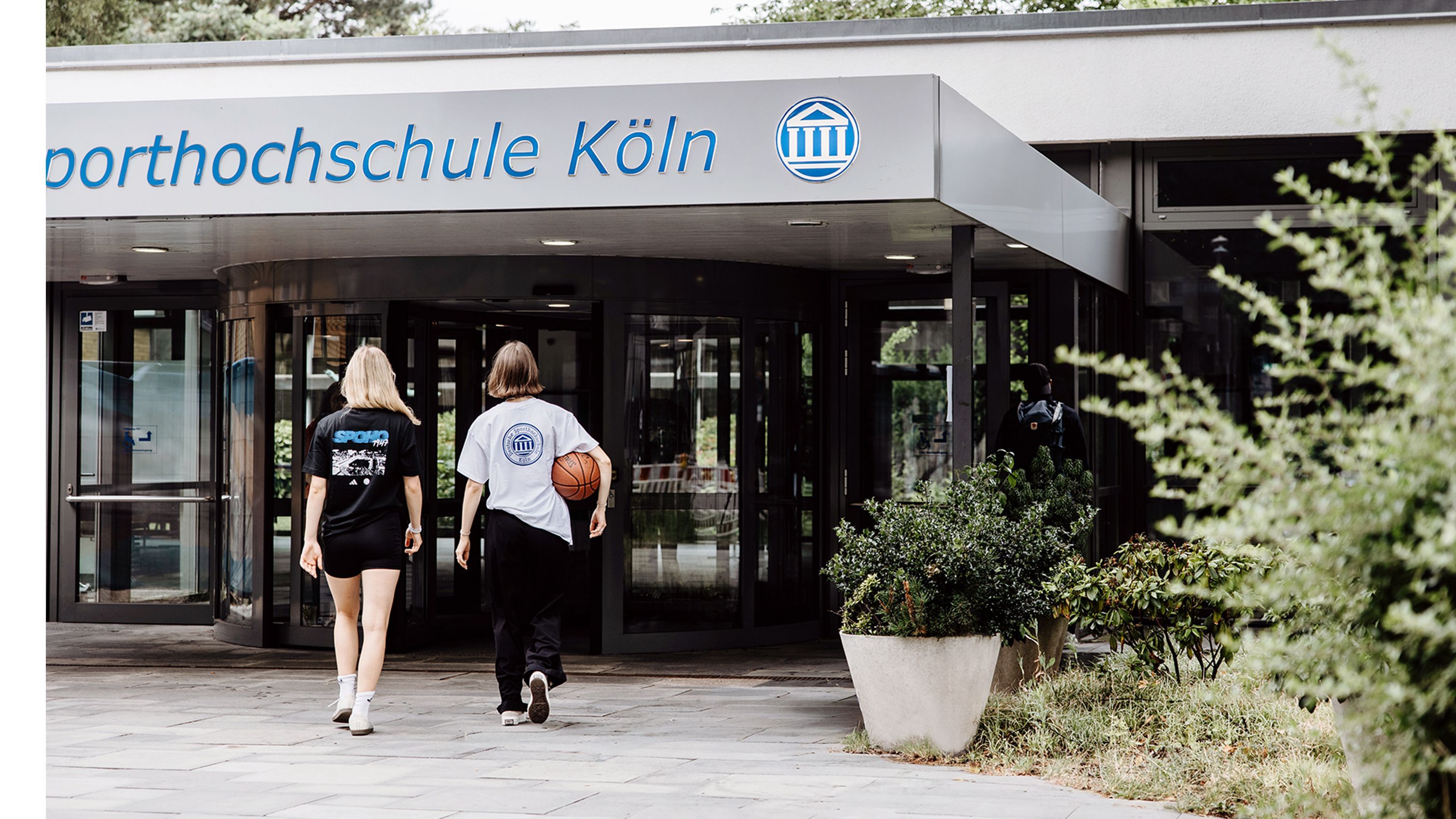 Zwei Studentinnen betreten die Uni über den Haupteingang
