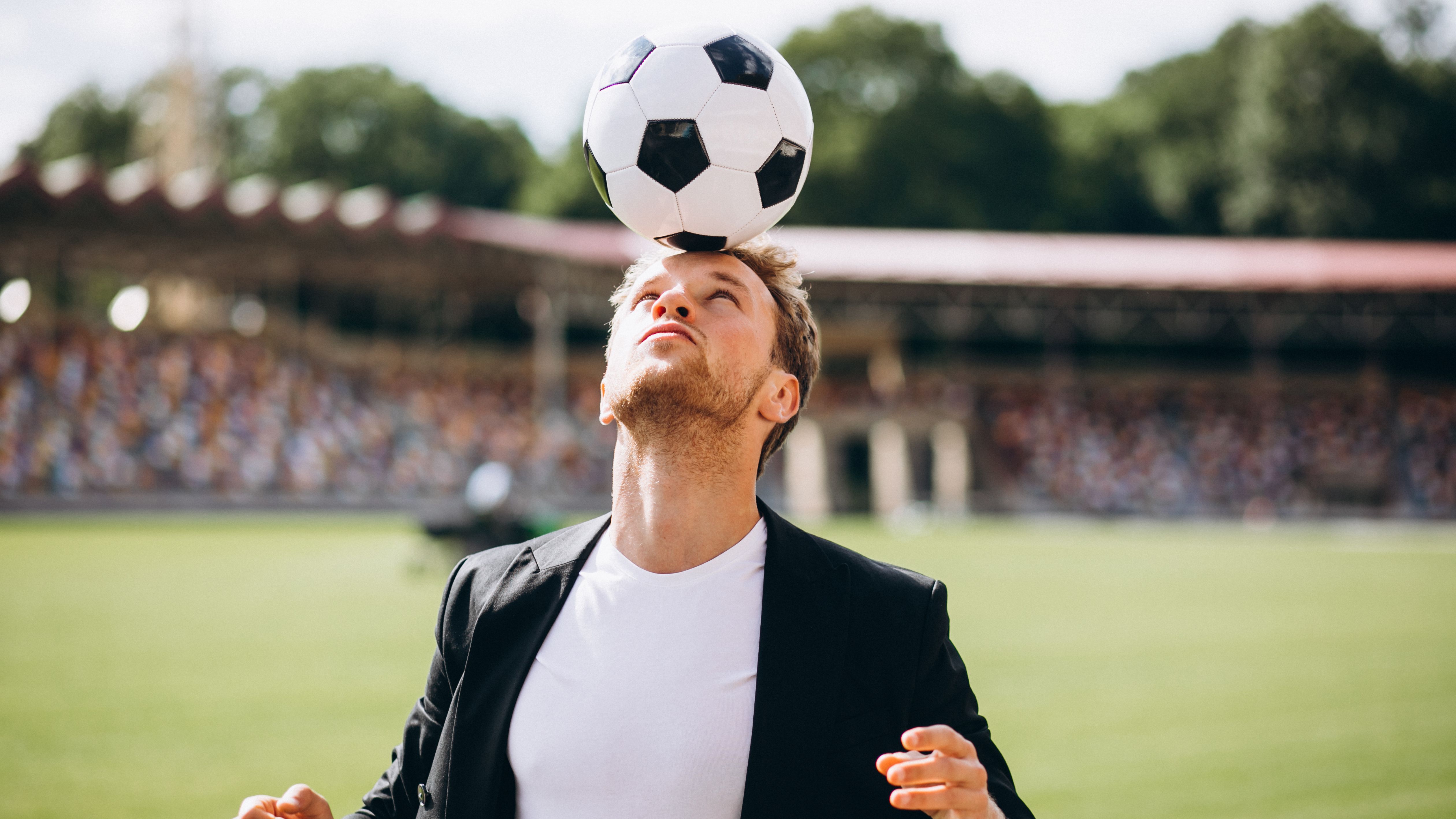 Manager balanciert Fußball auf dem Kopf.
