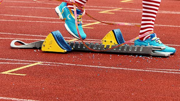 Person steht im Startblock und ist mit Luftschlangen um die Beine startbereit
