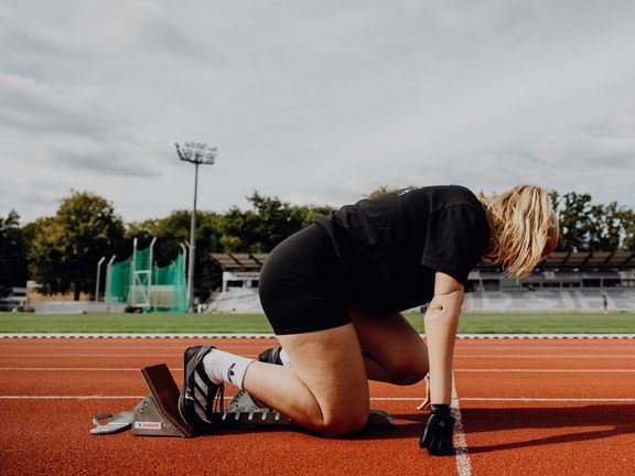 Seitliches Foto von Person die im Startblock bereit zum Start ist
