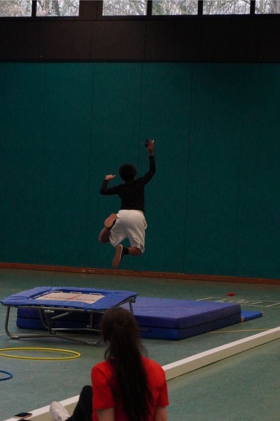 Kind springt von einem Mini-Trampolin auf eine Matte
