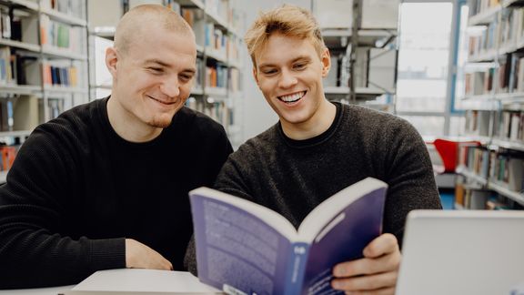 Zwei Studenten lesen ein Buch in der Bibliothek der Deutschen Sporthochschule
