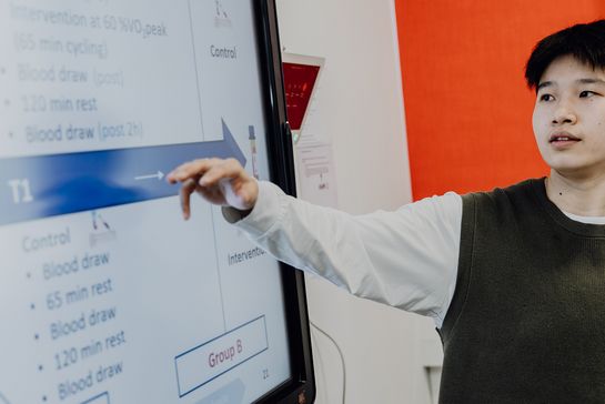 Person stellt Präsentation am großen Monitor vor
