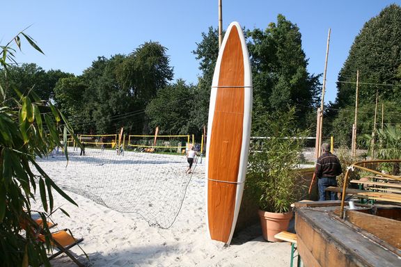 Ein Surfbrett steht im Biergarten der Beachsportanlage
