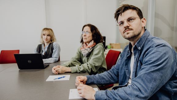 Personen blicken im Konferenzraum sitzend nach vorne
