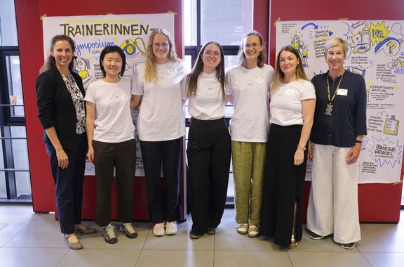 Gruppenfoto des Projektteams, sieben Personen stehen vor zwei Stellwänden mit Zeichnungen zur Veranstaltung
