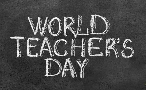 weiße Kreideschrift auf schwarzer Tafel "World Teacher's day" in Versalien
