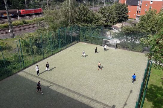 Bolzplatz von oben inmitten von Wohnhäusern und Bahngleisen