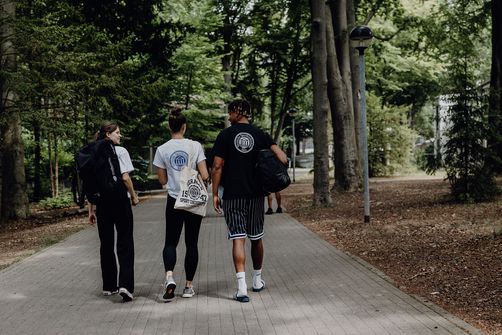 Drei Studierende laufen über den Außenbereich des Campus der Deutschen Sporthochschule
