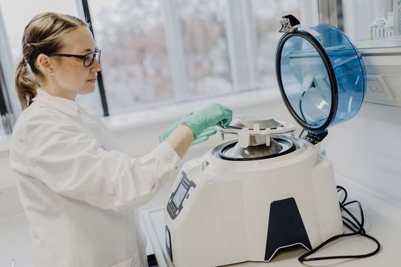 Eine Wissenschaftlerin steht im Labor an einem Gerät
