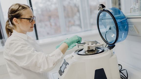 Eine Wissenschaftlerin aus der Biochemie steht im Labor an einem Gerät
