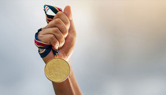 Hand hält Medaille an einem Band hoch
