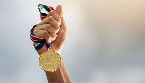 Hand hält Medaille an einem Band hoch
