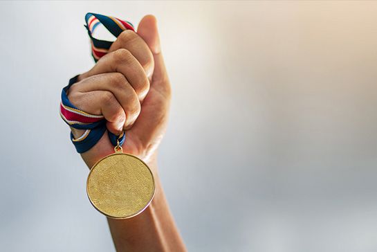 Hand hält Medaille an einem Band hoch
