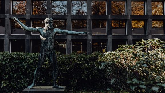 Außenbereich des Campus der Deutsche Sporthochschule mit steinerner Statue
