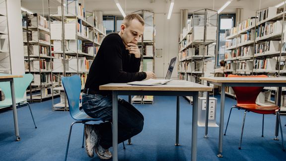 Student lernt in der Bibliothek der Deutschen Sporthochschule
