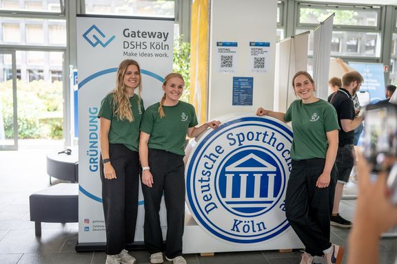 Die Gründerinnen von Fit O Saurus vor dem Logo der Deutschen Sporthochschule Köln
