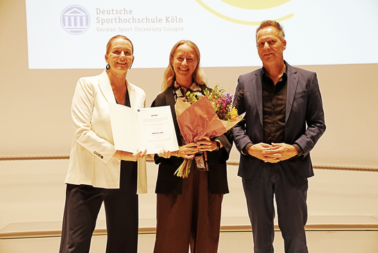 Drei Personen mit einer Urkunde und Blumen