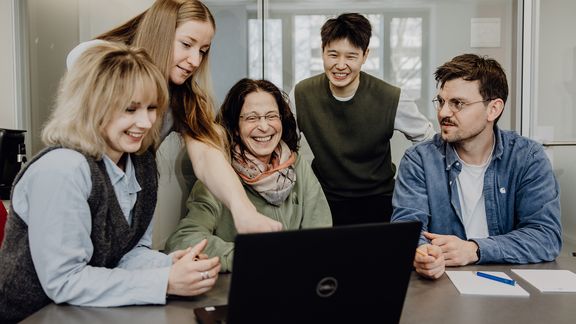 Personen betrachten lächelnd Inhalt auf einem Laptop
