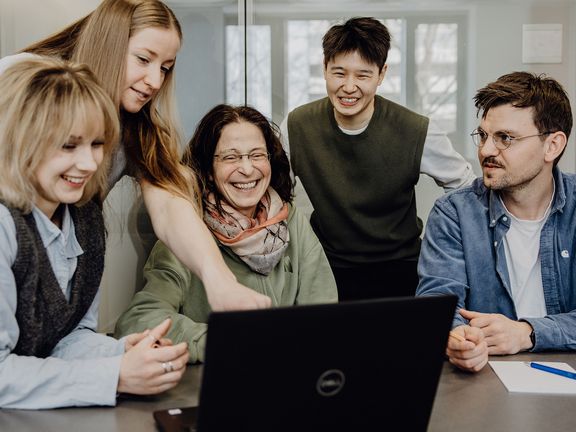 Personen betrachten lächelnd Inhalt auf einem Laptop
