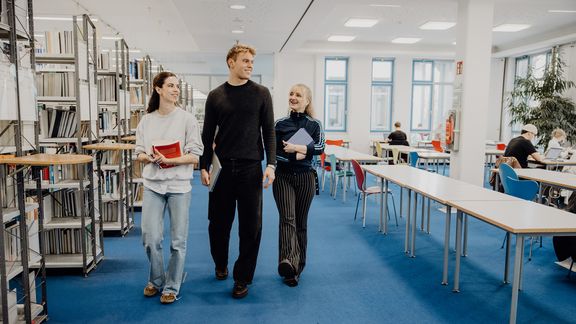 Drei Studierende laufen durch die Bibliothek der Deutschen Sporthochschule
