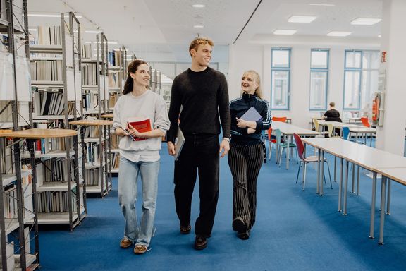 Drei Studierende laufen durch die Bibliothek der Deutschen Sporthochschule
