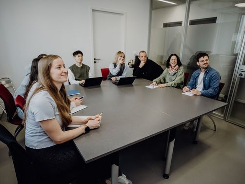 Personen blicken sitzend im Konferenzraum nach vorne
