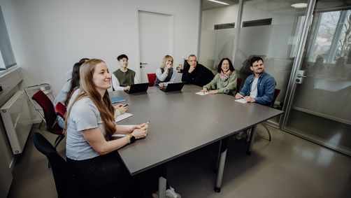 Personen blicken sitzend im Konferenzraum nach vorne
