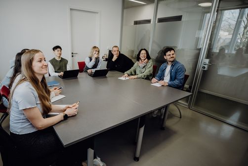 Personen blicken sitzend im Konferenzraum nach vorne
