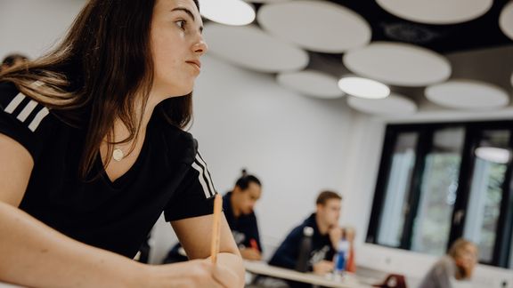 Studierende sitzen im Seminarraum und hören dem Unterricht zu
