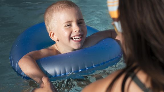 Kind beim Schwimmen mit seiner Mutter.
