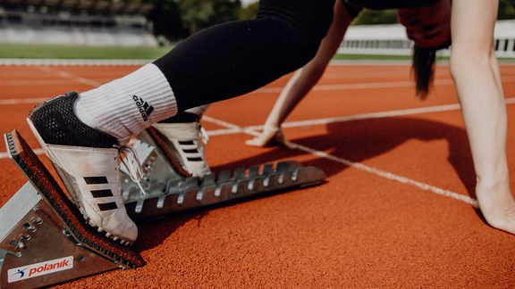 Nahaufnahme der Spike-Laufschuhe im Startblock auf der Laufbahn
