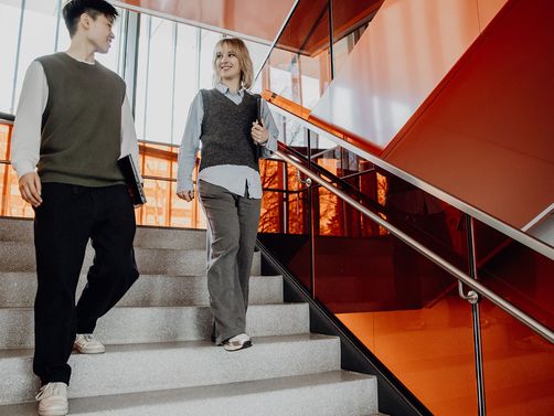 Zwei Studierende gehen zusammen die Treppen runter

