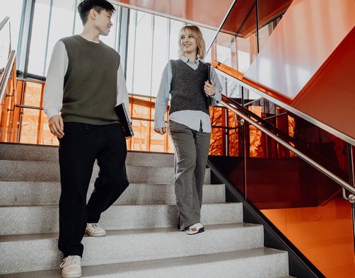 Zwei Studierende gehen zusammen die Treppen runter
