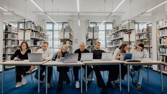 Studierende sitzen mit Laptops in der Bibliothek der Deutschen Sporthochschule
