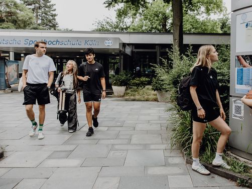 Zwei Studierende betrachten den Wegweiser im Eingangsbereich der Deutschen Sporthochschule

