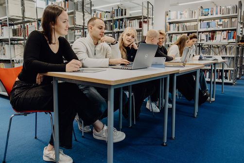 Studierende sitzen mit Laptops in der Bibliothek der Deutschen Sporthochschule
