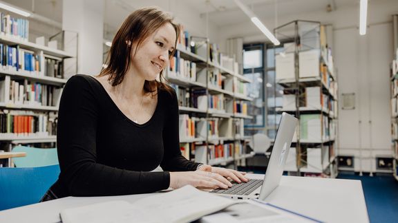 Studentin arbeitet mit Laptop in der Bibliothek der Deutschen Sporthochschule
