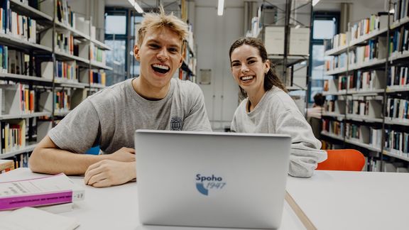 Zwei Studierende lachen in der Bibliothek der Deutschen Sporthochschule
