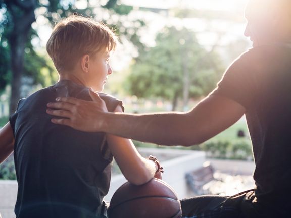 Junge mit Basketball und Trainer
