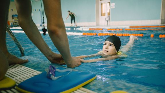 Kind im Wasser beim Schwimmenlernen.
