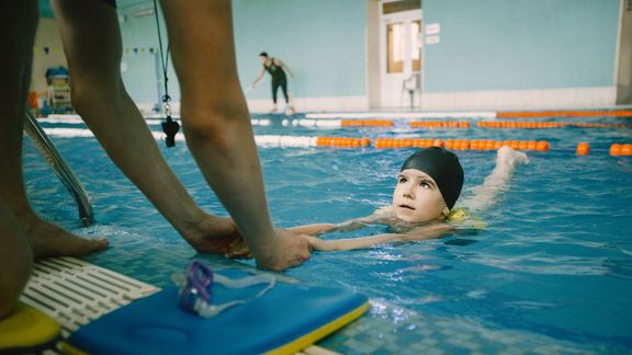 Kind im Wasser beim Schwimmenlernen.
