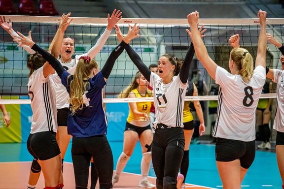 Kölner Frauenmannschaft jubelt vorm Volleyballnetz und tragen Trikots der Firma adidas
