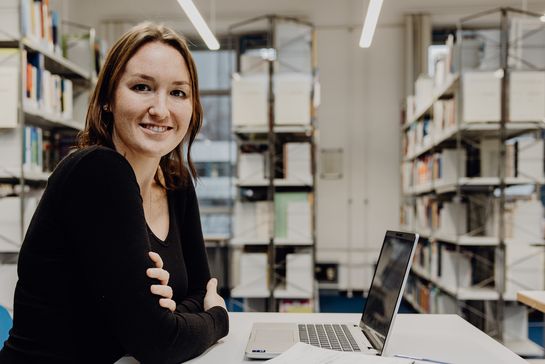 Studentin sitzt mit Laptop in der Bibliothek der Deutschen Sporthochschule